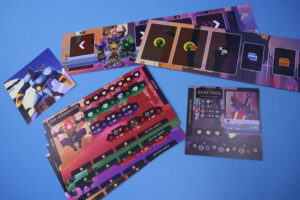 Ein Set aus verschiedenen Spielkarten und Spielbrettern auf einem blauen Hintergrund. Zu sehen sind Charakterkarten mit fantasievollen Illustrationen, darunter ein großer Roboter und verschiedene spielbezogene Symbole und Werte. Die Karten haben eine lebendige Farbgebung und scheinen zu einem strategischen Tischspiel zu gehören.